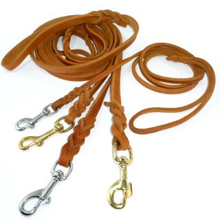 Drei geflochtene Modler Fettlederleinen in hellbraun, dunkelbraun und schwarz in verschiedenen Breiten und mit verschiedenen Bolzenhaken. Im Hintergrund Werkzeuge zum Leinen bauen.